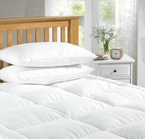 Cozy bedroom with white pillows and duvet on a wooden bed frame.