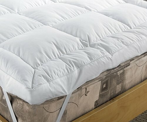 White mattress topper on a bed with wooden frame